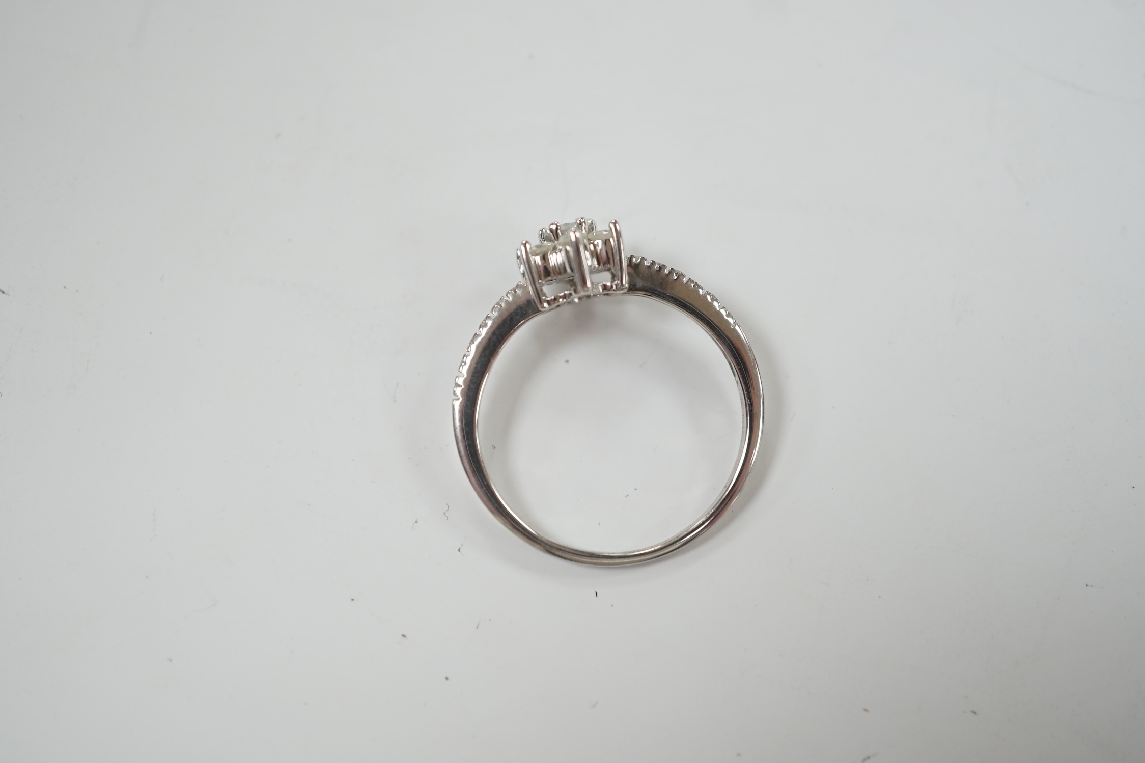 A modern 9ct white gold and diamond cluster set flower head ring, with diamond chip set shoulders, size R/S, gross weight 2.8 grams.